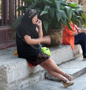 Caminin bahçesinde telefon muhabbeti yapan bir müslüman kadın.